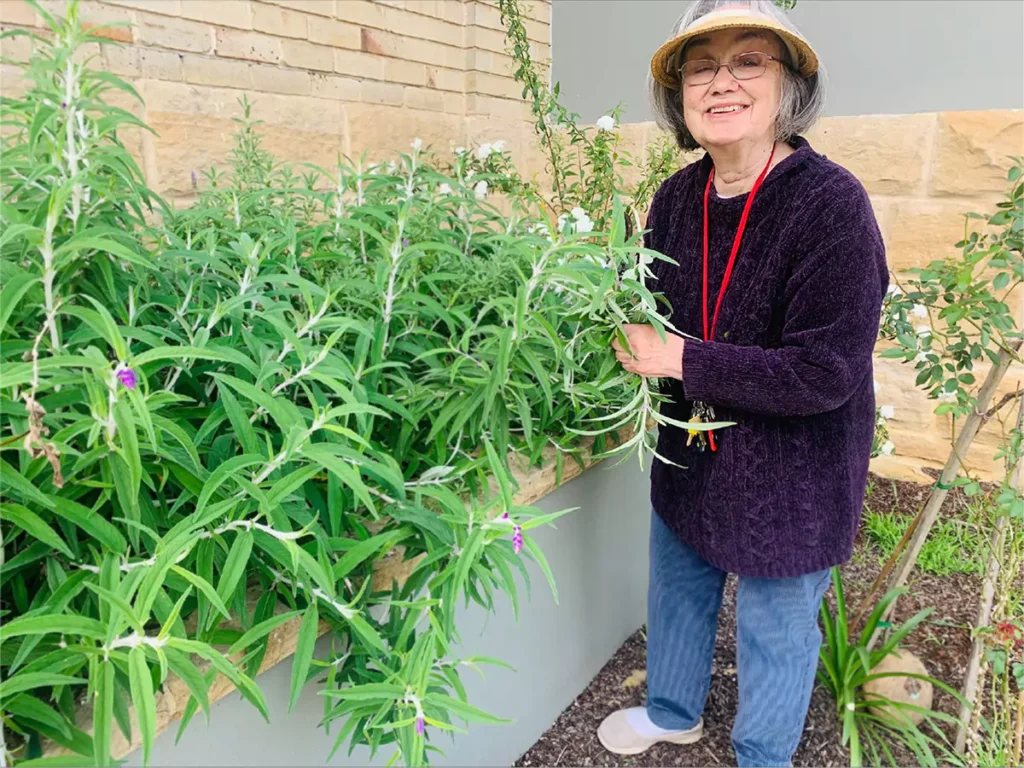Happy woman smiling at camera while gardening